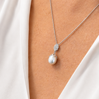 Pearl necklace with silver clasp on a person wearing a white top