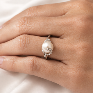 Pearl ring on a person's finger against a white background
