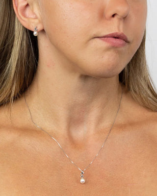 Close-up of a woman wearing a silver necklace with a pearl pendant.