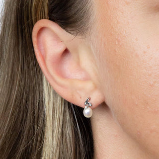 Close-up of an ear wearing a pearl earring with a delicate setting.