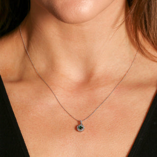 Necklace with a pendant featuring a green gemstone worn by a person.