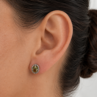 Close-up of an ear wearing a green gemstone earring with a blurred background