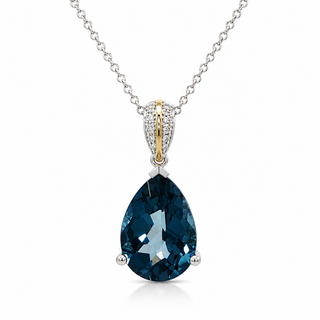 A teardrop-shaped dark blue gemstone pendant necklace on a silver chain, featuring a gold and silver pavé bail with a central gold stripe.