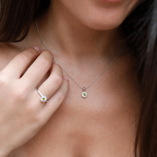 Close-up of a necklace with a pendant worn by a person, with a hand touching the neck.