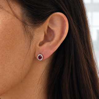 Close-up of an ear wearing a red gemstone earring with a blurred background