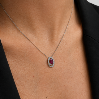 Necklace with a red gemstone pendant on a person wearing a black outfit.