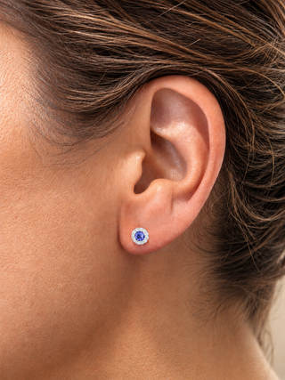 Close-up of an ear wearing a blue gemstone earring with a blurred background