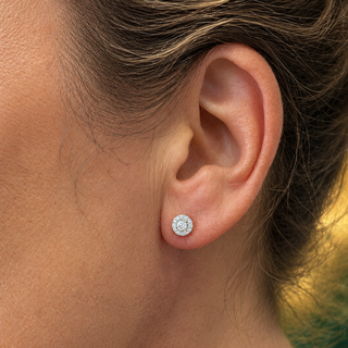 Close-up of an ear wearing a diamond stud earring with a blurred background