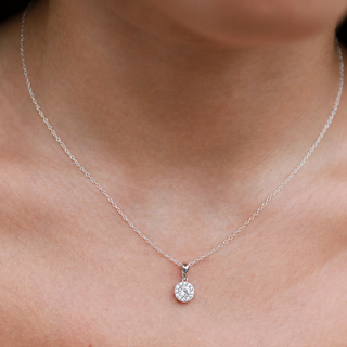 Silver necklace with a round pendant on a person's neck