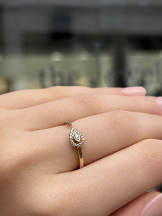 Gold ring with a diamond on a person's finger against a blurred background