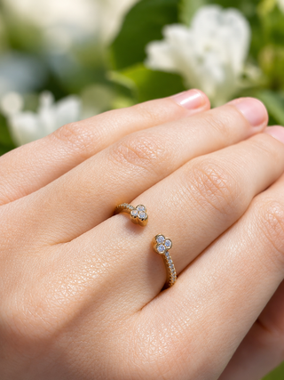 Close-up of a hand wearing two diamond rings with a blurred floral background