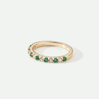 Gold ring with green gemstones on a white background