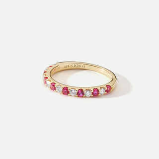 Gold ring with red and white gemstones on a light background