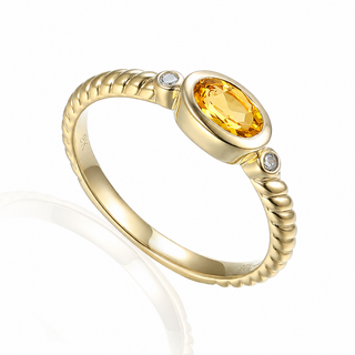 A yellow gold ring with a textured twisted band, featuring a large oval-cut yellow citrine center stone and two small round-cut diamond accents on either side, set against a clean white background.