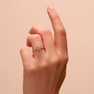 Hand wearing a diamond ring on a beige background