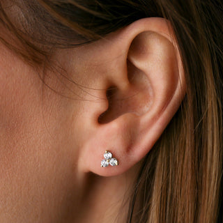 Close-up of an ear wearing a silver earring with three small diamonds.