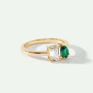 Gold ring with emerald and diamond on a white background