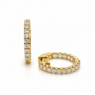 A pair of gold huggie hoop earrings set with round-cut clear gemstones, shown from both a side profile and a front-facing angle on a clean white background.