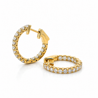 A pair of gold hoop earrings set with clear pavé diamonds, shown on a clean white background. One earring is angled to show the post and clasp, while the other is shown from the side, displaying the continuous row of sparkling stones.