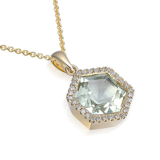 Gold necklace with a green gemstone pendant on a white background