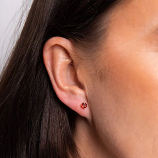 Close-up of an ear wearing a red earring with dark hair and skin.