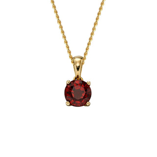 Gold necklace with a red gemstone pendant on a white background