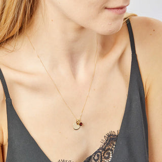 Close-up of a woman wearing a delicate gold necklace with small round pendants.