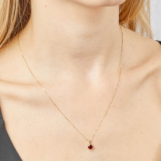 Gold necklace with a red gemstone pendant on a person's neck