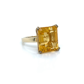 Gold ring with a large yellow gemstone on a white background