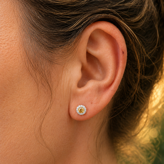 Close-up of an ear wearing a sunflower-themed earring with a blurred natural background