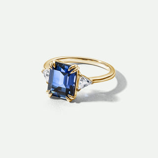Gold ring with a blue gemstone on a white background