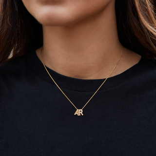 Gold necklace with 'AR' pendant on a black shirt