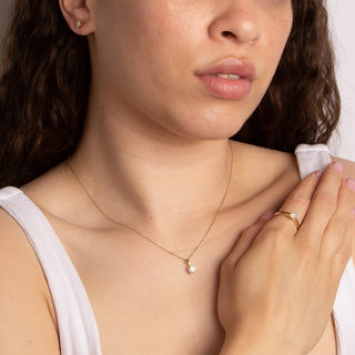 Close-up of a woman wearing a gold necklace with a small pendant.