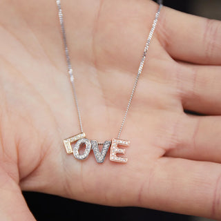Necklace with 'LOVE' pendant held in a hand