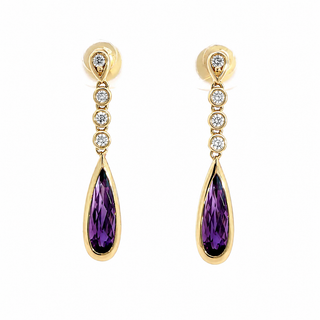 A pair of gold dangle earrings with a teardrop-shaped purple amethyst center stone and four small clear round-cut stones above it, set against a plain white background.