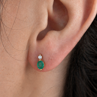 Close-up of an ear wearing a green gemstone earring with a diamond.