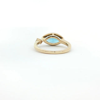 A gold ring featuring a marquise-cut light blue gemstone in a split setting, shown on a plain white background.