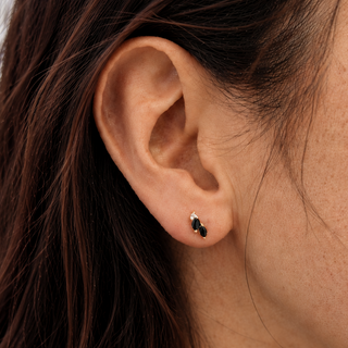 Close-up of an ear wearing a small earring with dark blue sapphires.