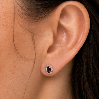 Close-up of an ear wearing a stud earring with a red gemstone.