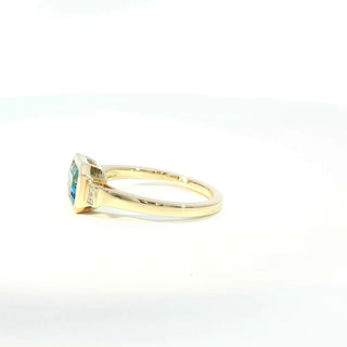 A yellow gold ring featuring a square-cut light blue gemstone, shown in a side profile view against a plain white background.