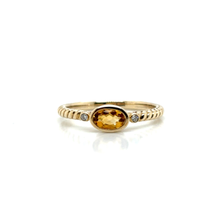 Gold ring with a yellow gemstone on a white background