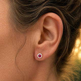 Close-up of an ear wearing a red gemstone earring with a blurred natural background