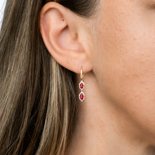 Close-up of a woman wearing a gold earring with red gemstones.
