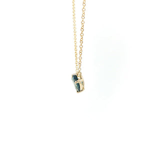 A delicate gold chain necklace with a small pendant featuring a dark blue pear-cut gemstone set in a gold frame, shown against a plain white background.