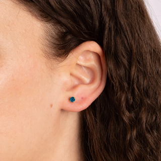 Close-up of an ear with a small blue gemstone earring.