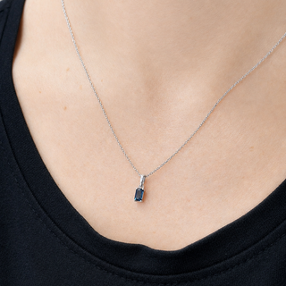 Silver necklace with a pendant on a person wearing a black top.