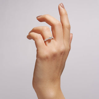 Hand wearing a diamond ring on a plain background