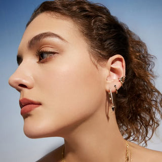 Close-up of a woman's face with earrings against a clear blue sky