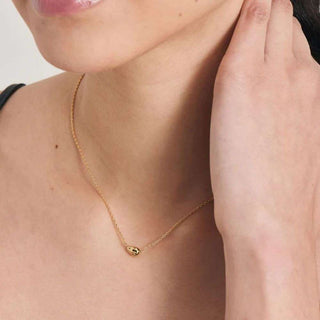 Gold necklace worn by a person with a neutral background