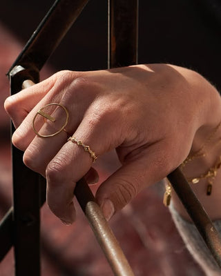 Hand wearing gold rings on a blurred background
